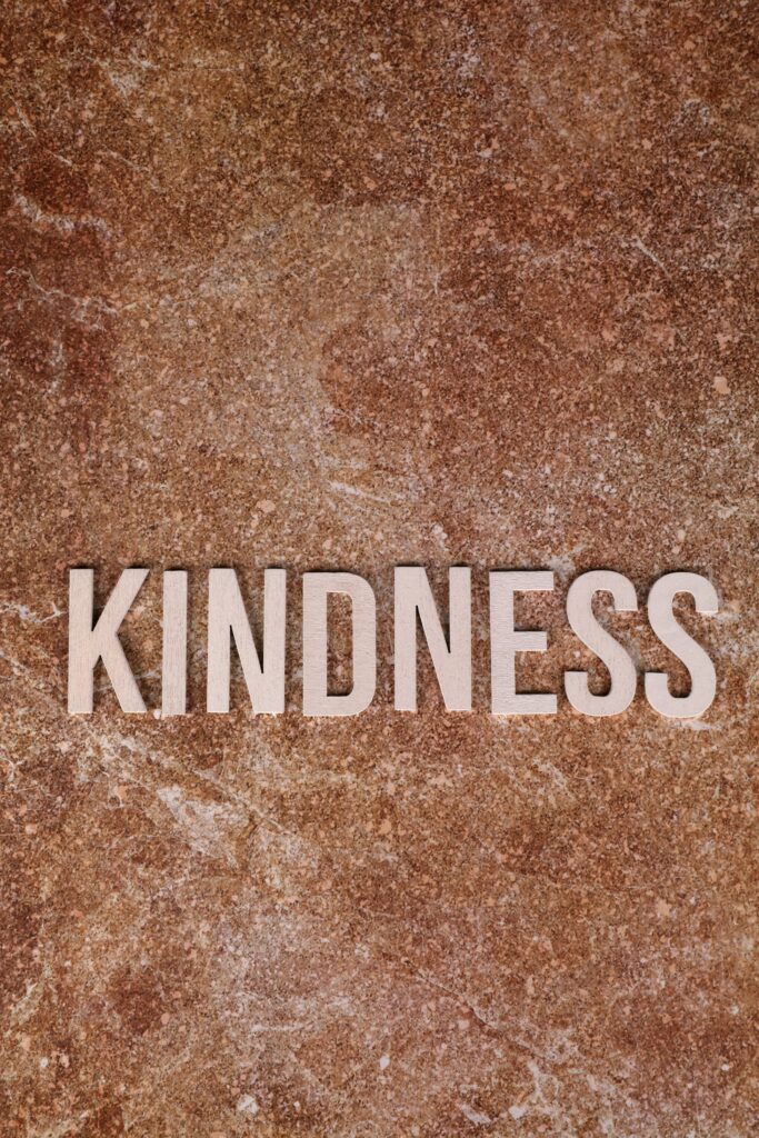Text 'Kindness' on a brown textured surface conveying warmth and empathy.